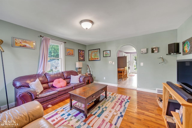 622 Kendon Dr, Lansing, MI 48910 - living room featuring arched walkways, light wood finished floors, and baseboards