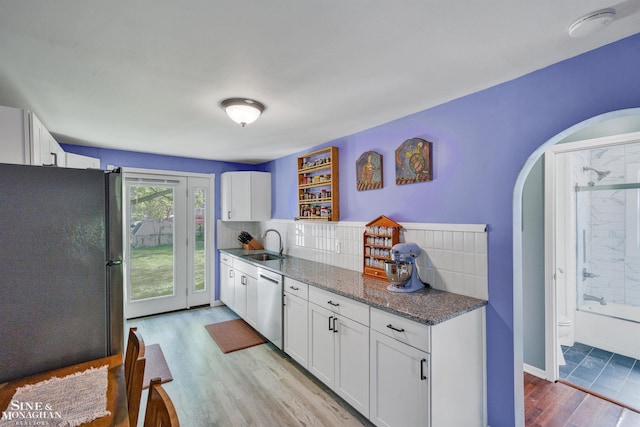 622 Kendon Dr, Lansing, MI 48910 - kitchen with freestanding refrigerator, a sink, light wood-type flooring, dishwasher, and arched walkways