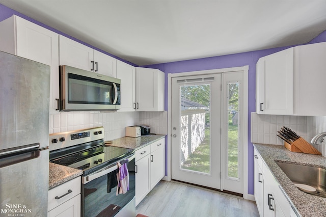622 Kendon Dr, Lansing, MI 48910 - kitchen with appliances with stainless steel finishes, a sink, decorative backsplash, white cabinets, and light wood-style floors