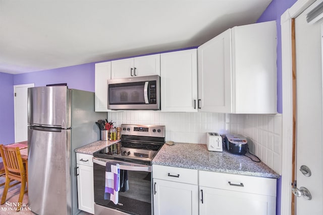 622 Kendon Dr, Lansing, MI 48910 - kitchen featuring stainless steel appliances, backsplash, white cabinets, and light stone countertops
