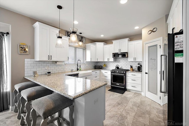 29696 Kevin Rd, New Baltimore, MI 48051 - kitchen with black gas stove, a peninsula, backsplash, white cabinets, and light stone counters