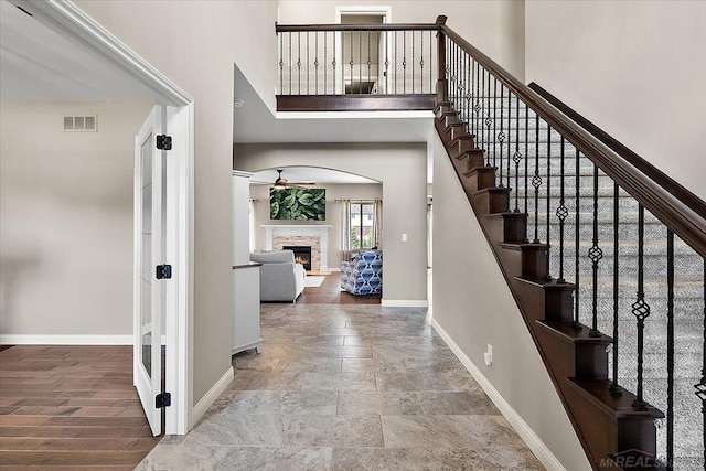 29696 Kevin Rd, New Baltimore, MI 48051 - stairway featuring baseboards, stone finish flooring, a warm lit fireplace, a towering ceiling, and ceiling fan