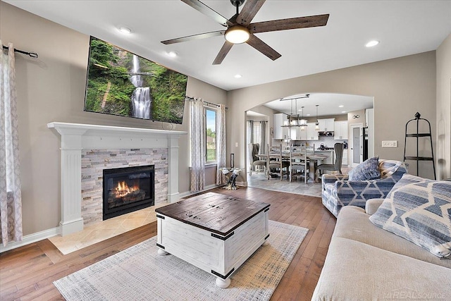 29696 Kevin Rd, New Baltimore, MI 48051 - living area featuring arched walkways, light wood finished floors, a ceiling fan, a fireplace with flush hearth, and recessed lighting
