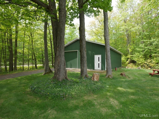 26514 Hendrickson Rd, Calumet, MI 49913 - view of side of home featuring a lawn, a detached garage, and an outdoor structure