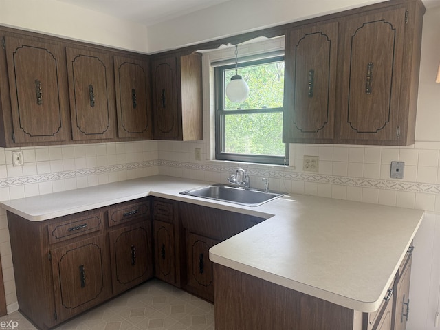26167 Fairfield Ave, Warren, MI 48089 - kitchen featuring a sink, a peninsula, light countertops, and backsplash