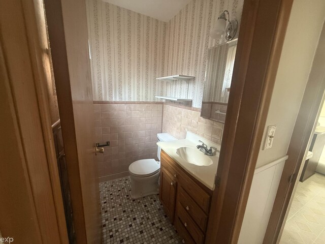 26167 Fairfield Ave, Warren, MI 48089 - half bath featuring vanity, tile patterned flooring, toilet, wallpapered walls, and a wainscoted wall
