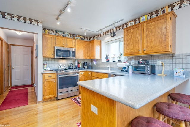 518 Lexington Dr, Rochester Hills, MI 48307 - kitchen with stainless steel appliances, a peninsula, light countertops, light wood finished floors, and a breakfast bar