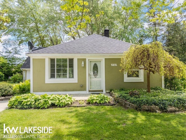 7184 Baker Rd, Worth Twp, MI 48450 - bungalow-style home with a shingled roof, a chimney, and a front lawn