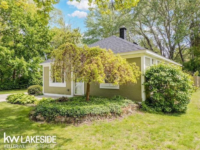 7184 Baker Rd, Worth Twp, MI 48450 - view of side of home featuring a shingled roof, a lawn, stucco siding, and a chimney
