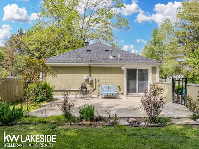7184 Baker Rd, Worth Twp, MI 48450 - rear view of property featuring roof with shingles, a patio area, concrete block siding, and a gate