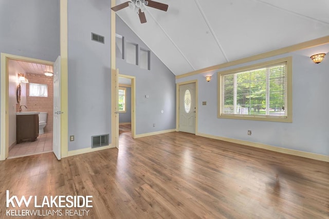 7184 Baker Rd, Worth Twp, MI 48450 - unfurnished living room featuring high vaulted ceiling, ceiling fan, wood finished floors, baseboards, and brick wall