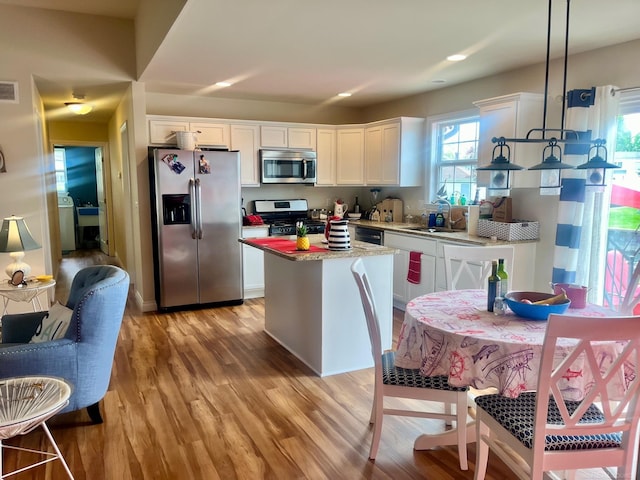 727 Townsend Dr, Algonac, MI 48001 - kitchen with stainless steel appliances, light wood-type flooring, white cabinets, a kitchen island, and hanging light fixtures