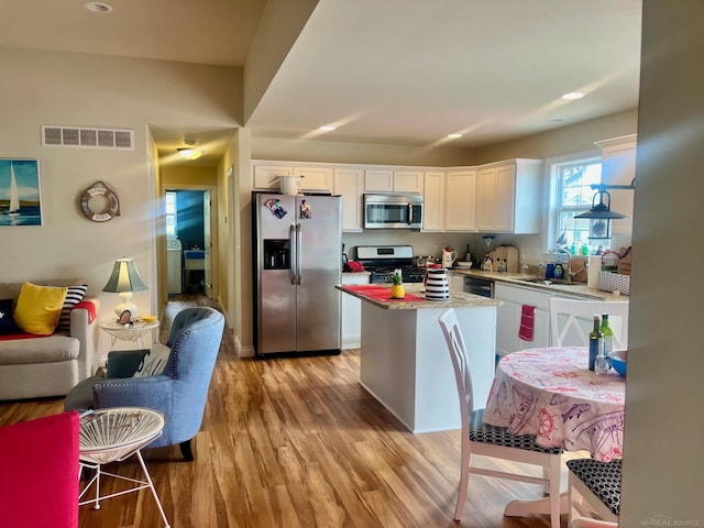 727 Townsend Dr, Algonac, MI 48001 - kitchen featuring appliances with stainless steel finishes, white cabinetry, light wood finished floors, a kitchen island, and recessed lighting