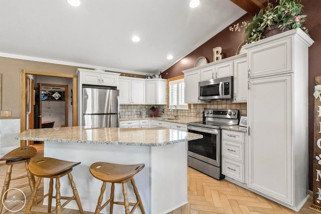 7360 Frith Rd, Saint Clair, MI 48079 - kitchen featuring stainless steel appliances, a breakfast bar, white cabinets, a kitchen island, and lofted ceiling
