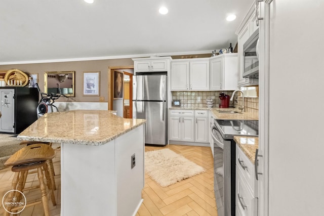 7360 Frith Rd, Saint Clair, MI 48079 - kitchen with stainless steel appliances, a sink, white cabinetry, a center island, and decorative backsplash