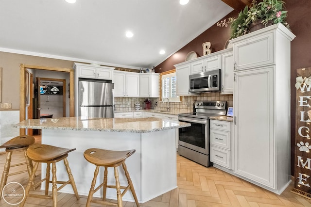 7360 Frith Rd, Saint Clair, MI 48079 - kitchen with stainless steel appliances, a kitchen island, white cabinets, a breakfast bar, and vaulted ceiling