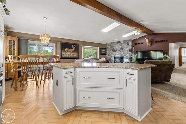 7360 Frith Rd, Saint Clair, MI 48079 - kitchen with a stone fireplace, open floor plan, white cabinets, a ceiling fan, and light stone countertops