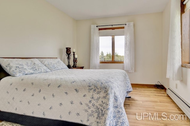 12104 T Rd, Rapid River, MI 49878 - bedroom featuring a baseboard heating unit, light wood-style floors, and baseboards