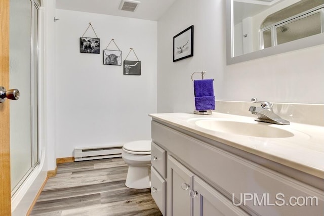 12104 T Rd, Rapid River, MI 49878 - full bathroom with a baseboard heating unit, vanity, a shower stall, toilet, and wood finished floors