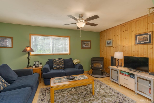 4427 Tip Up Trl, Eagle River, WI 54521 - living area featuring a wood stove, wooden walls, a ceiling fan, and light wood-type flooring