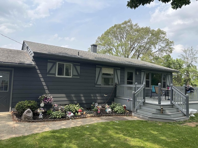 73 S Tuscola Rd, Bay City, MI 48708 - view of front facade with a front yard, a chimney, a wooden deck, and a shingled roof