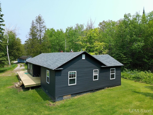 2731 W Jones Rd, Gulliver, MI 49840 - view of property exterior with a lawn, a shingled roof, a deck, and a view of trees