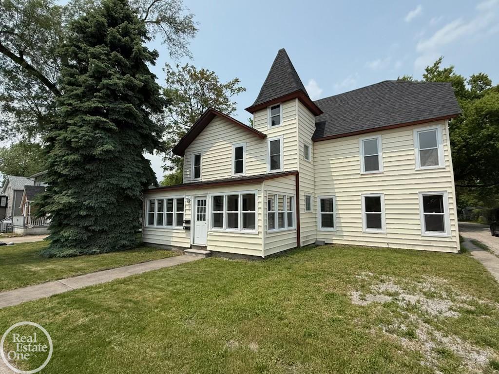 823 Beard St, Port Huron, MI 48060 - back of house with entry steps, roof with shingles, and a lawn