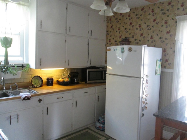 337 N 2nd St, Marine City, MI 48039 - kitchen with freestanding refrigerator, stainless steel microwave, wallpapered walls, ceiling fan, and white cabinetry