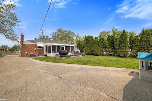 13040 Common Rd, Warren, MI 48088 - back of house featuring a sunroom, a patio, brick siding, central air condition unit, and a chimney
