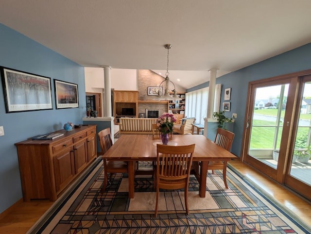 5663 Macintosh Dr, Bay City, MI 48706 - dining room with decorative columns, light wood-style flooring, a fireplace, vaulted ceiling, and a chandelier