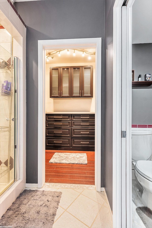33473 Mulvey Rd, Fraser, MI 48026 - full bathroom with toilet, tile patterned floors, a stall shower, rail lighting, and baseboards