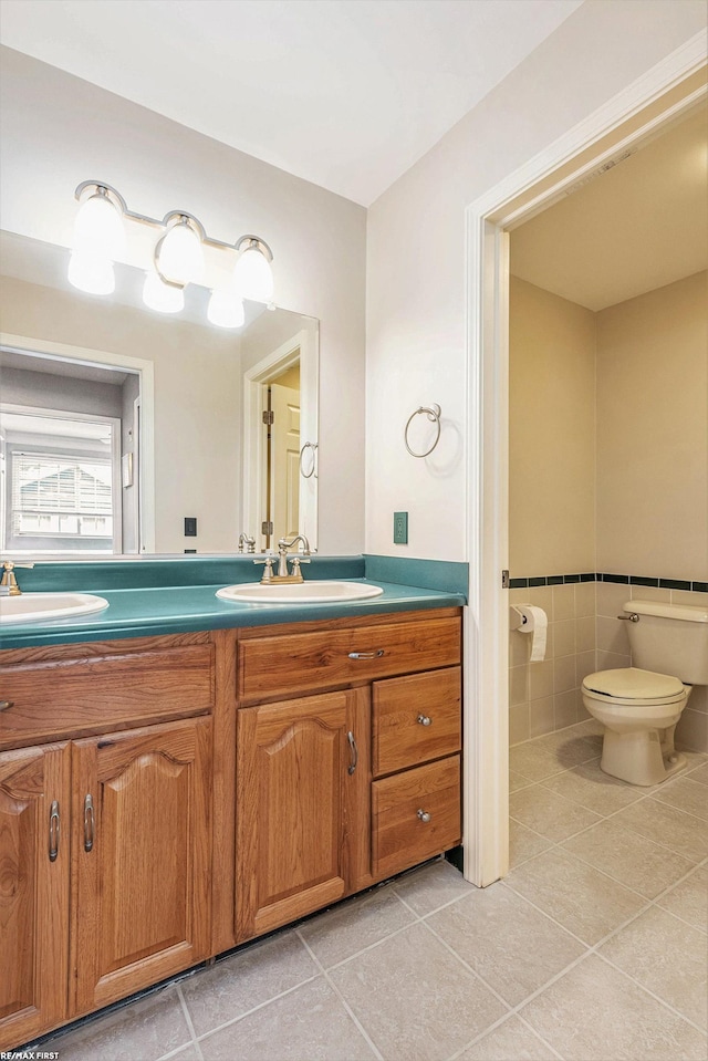 33473 Mulvey Rd, Fraser, MI 48026 - bathroom featuring double vanity, tile patterned floors, toilet, tile walls, and a wainscoted wall
