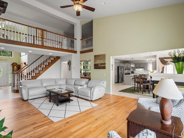 15158 Towering Oaks Dr, Shelby Twp, MI 48315 - living room with a high ceiling, light wood-style floors, ceiling fan, stairs, and a chandelier
