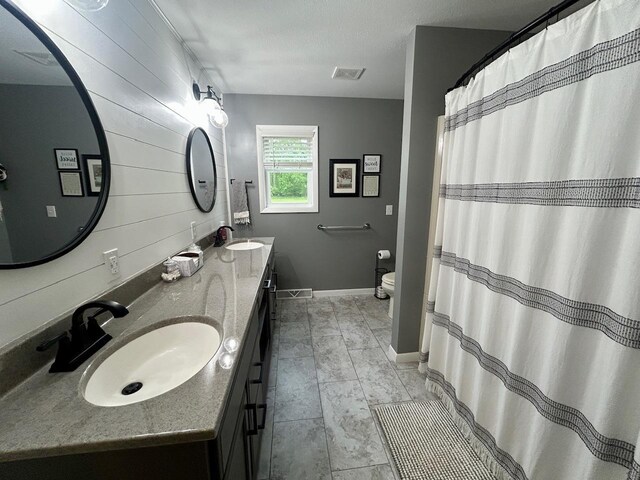 6586 N Coleman Rd, Coleman, MI 48618 - full bath featuring double vanity, toilet, baseboards, and wood walls