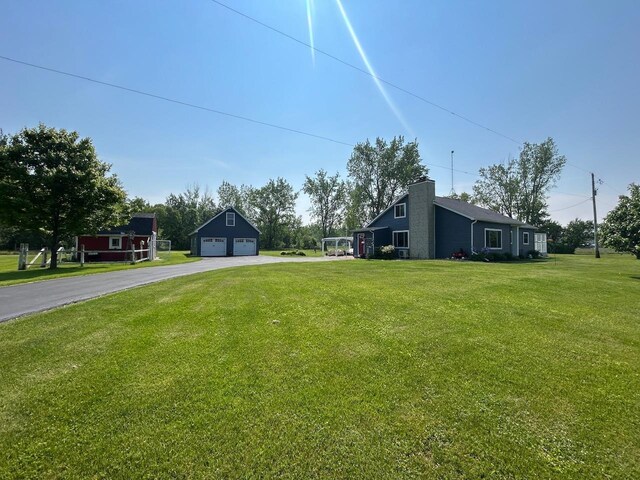 6586 N Coleman Rd, Coleman, MI 48618 - view of green lawn with a garage and an outbuilding