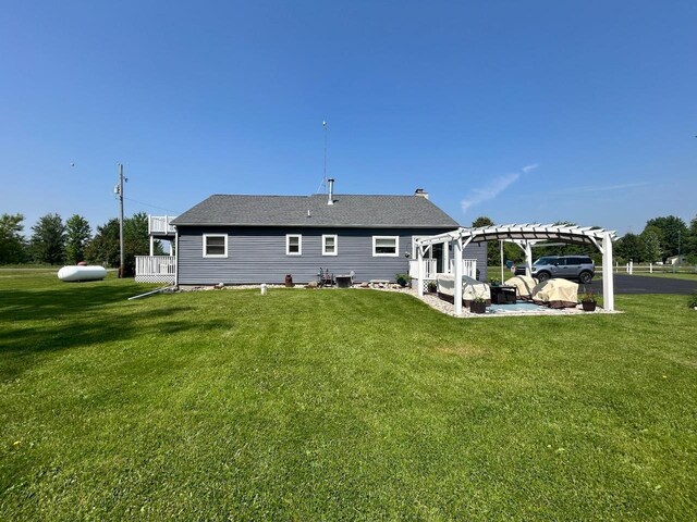 6586 N Coleman Rd, Coleman, MI 48618 - rear view of house featuring a pergola, a lawn, a shingled roof, and a patio