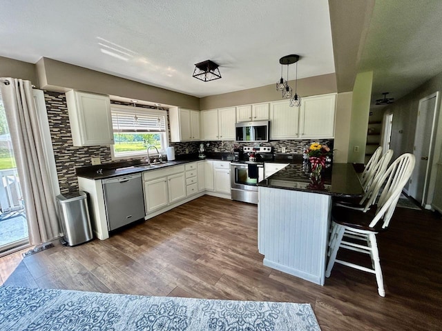 6586 N Coleman Rd, Coleman, MI 48618 - kitchen featuring stainless steel appliances, dark countertops, tasteful backsplash, a peninsula, and white cabinetry
