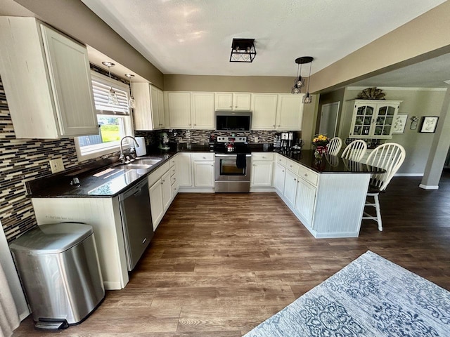 6586 N Coleman Rd, Coleman, MI 48618 - kitchen featuring stainless steel appliances, a sink, dark countertops, a peninsula, and backsplash