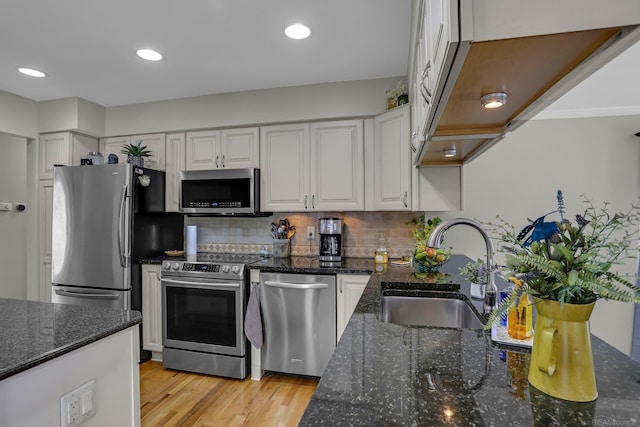 28052 Loretta Ave, Warren, MI 48092 - kitchen with appliances with stainless steel finishes, a sink, white cabinets, light wood-style flooring, and decorative backsplash