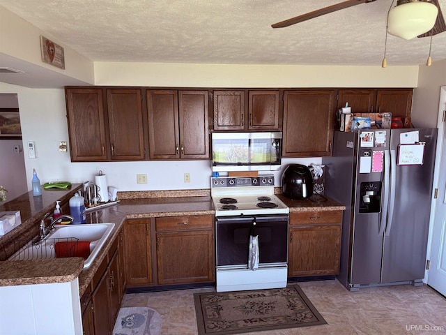8096 Garth Point 25.25 Ln Rd, Rapid River, MI 49878 - kitchen featuring appliances with stainless steel finishes, a sink, a textured ceiling, a peninsula, and dark countertops