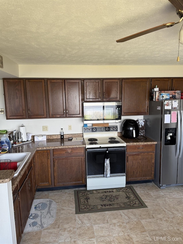 8096 Garth Point 25.25 Ln Rd, Rapid River, MI 49878 - kitchen with appliances with stainless steel finishes, a sink, a textured ceiling, dark brown cabinetry, and ceiling fan