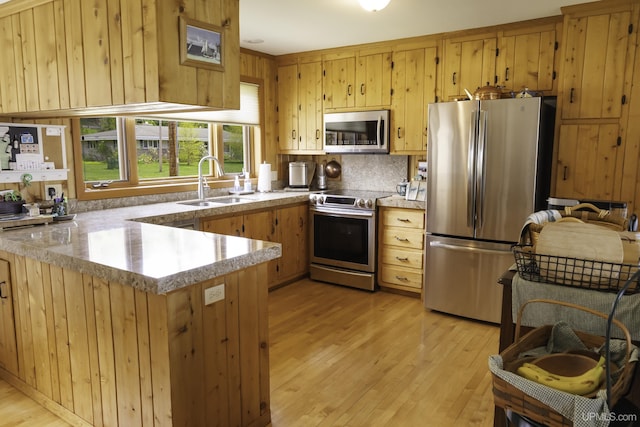 1426 Washington St, Munising, MI 49862 - kitchen with stainless steel appliances, a sink, light wood-style flooring, a peninsula, and light countertops