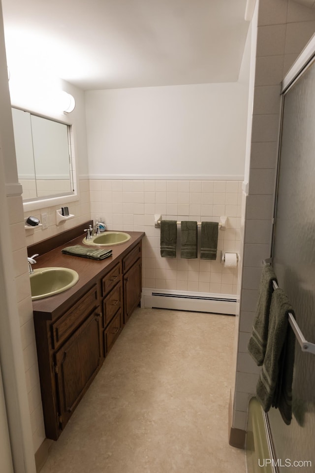 1426 Washington St, Munising, MI 49862 - bathroom featuring baseboard heating, tile walls, double vanity, and a wainscoted wall