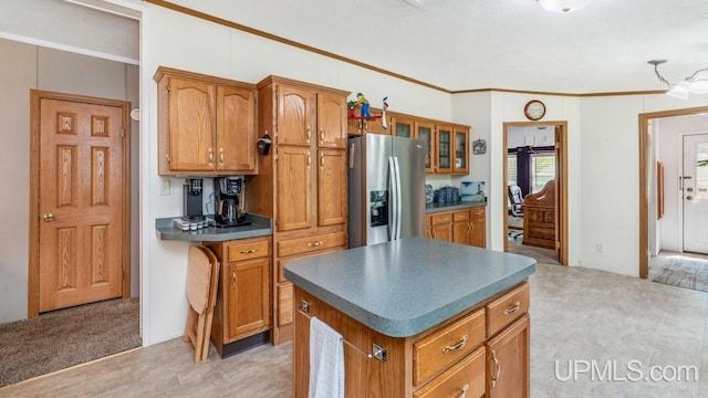 11745 T Rd, Rapid River, MI 49878 - kitchen with stainless steel refrigerator with ice dispenser, brown cabinets, ornamental molding, dark countertops, and a kitchen island