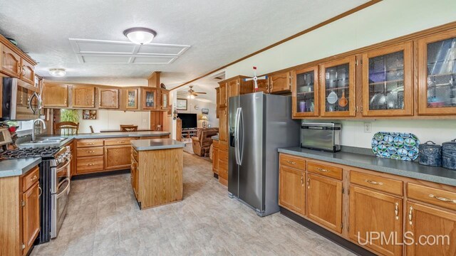 11745 T Rd, Rapid River, MI 49878 - kitchen with appliances with stainless steel finishes, brown cabinets, a center island, a sink, and glass insert cabinets
