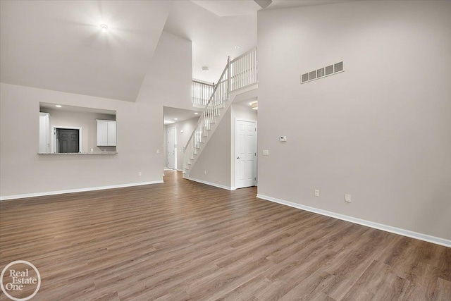 3095 Bridgewater Rd Unit # 30, Auburn Hills, MI 48326 - unfurnished living room featuring a high ceiling, wood finished floors, baseboards, and stairway