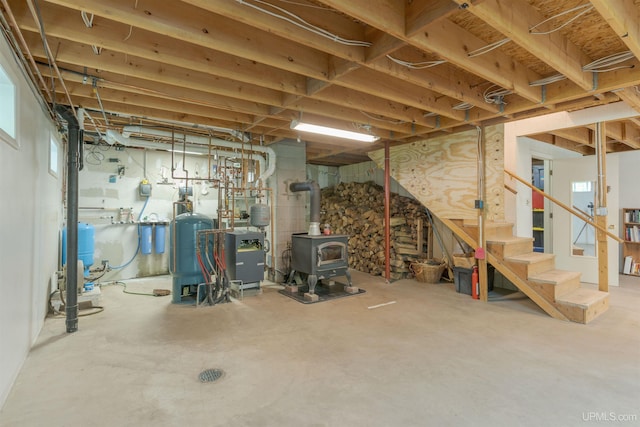 12826 Section 16 Rd, Watton, MI 49970 - below grade area with a wood stove, stairway, and a water pressure tank