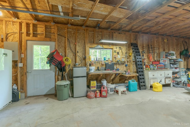 12826 Section 16 Rd, Watton, MI 49970 - garage featuring freestanding refrigerator, a workshop area, and electric panel