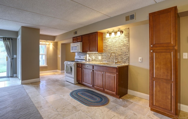 7859 Pine Ridge Dr, Clarkston, MI 48346 - kitchen with white appliances, a sink, backsplash, light stone counters, and baseboards