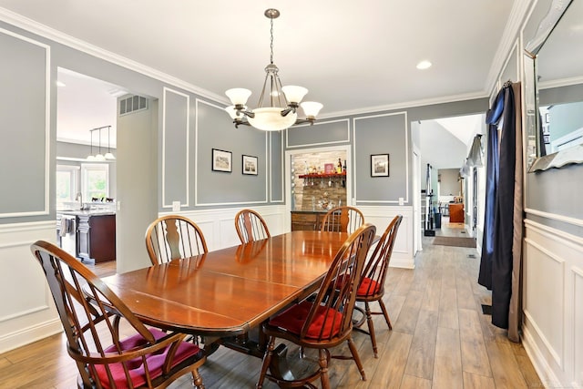 7859 Pine Ridge Dr, Clarkston, MI 48346 - dining room featuring a decorative wall, a chandelier, ornamental molding, and light wood-style floors